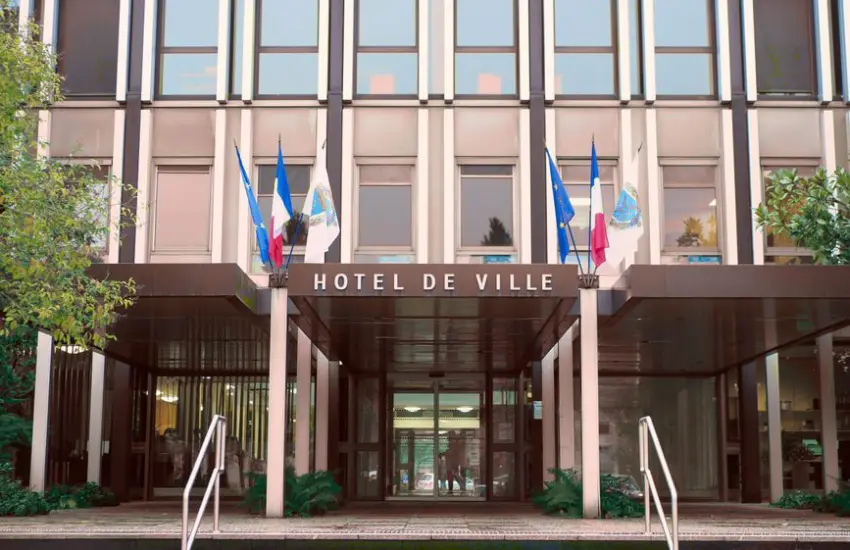 Front view of Hotel de Ville in Vélizy-Villacoublay, France with flags and modern architecture.