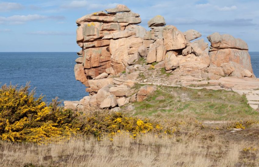 Stunning granite cliffs and coastal landscape at Plougrescant, Brittany, France under bright blue skies.